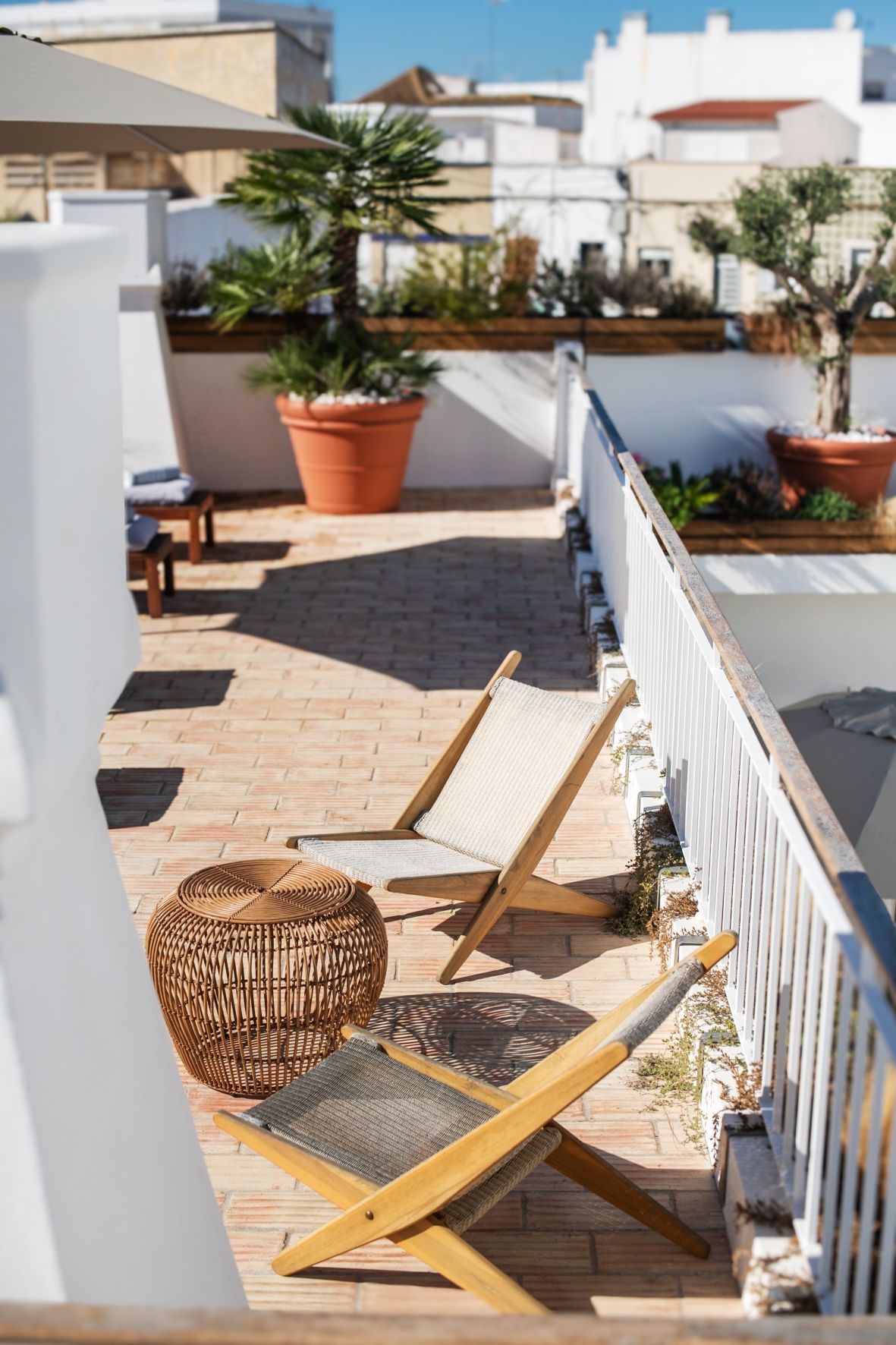 a balcony with chairs , umbrellas and potted plants .