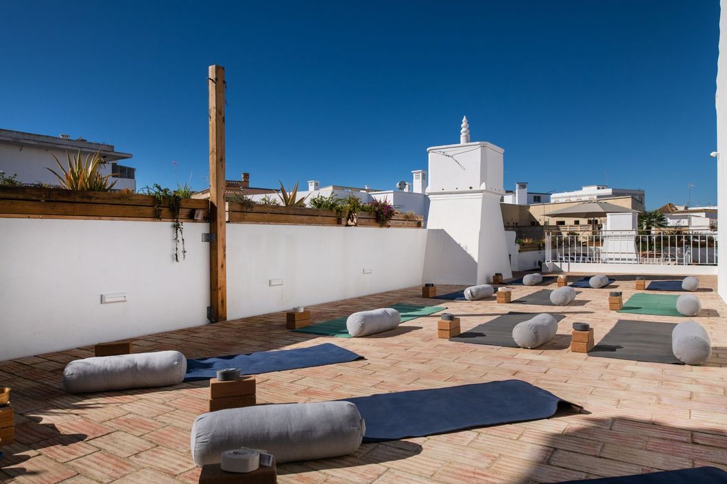 A rooftop with yoga mats and pillows on it