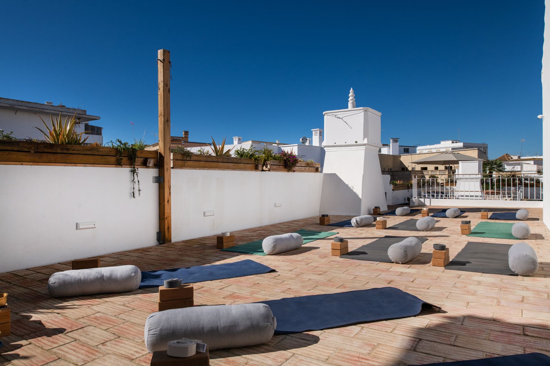 A rooftop with yoga mats and pillows on it