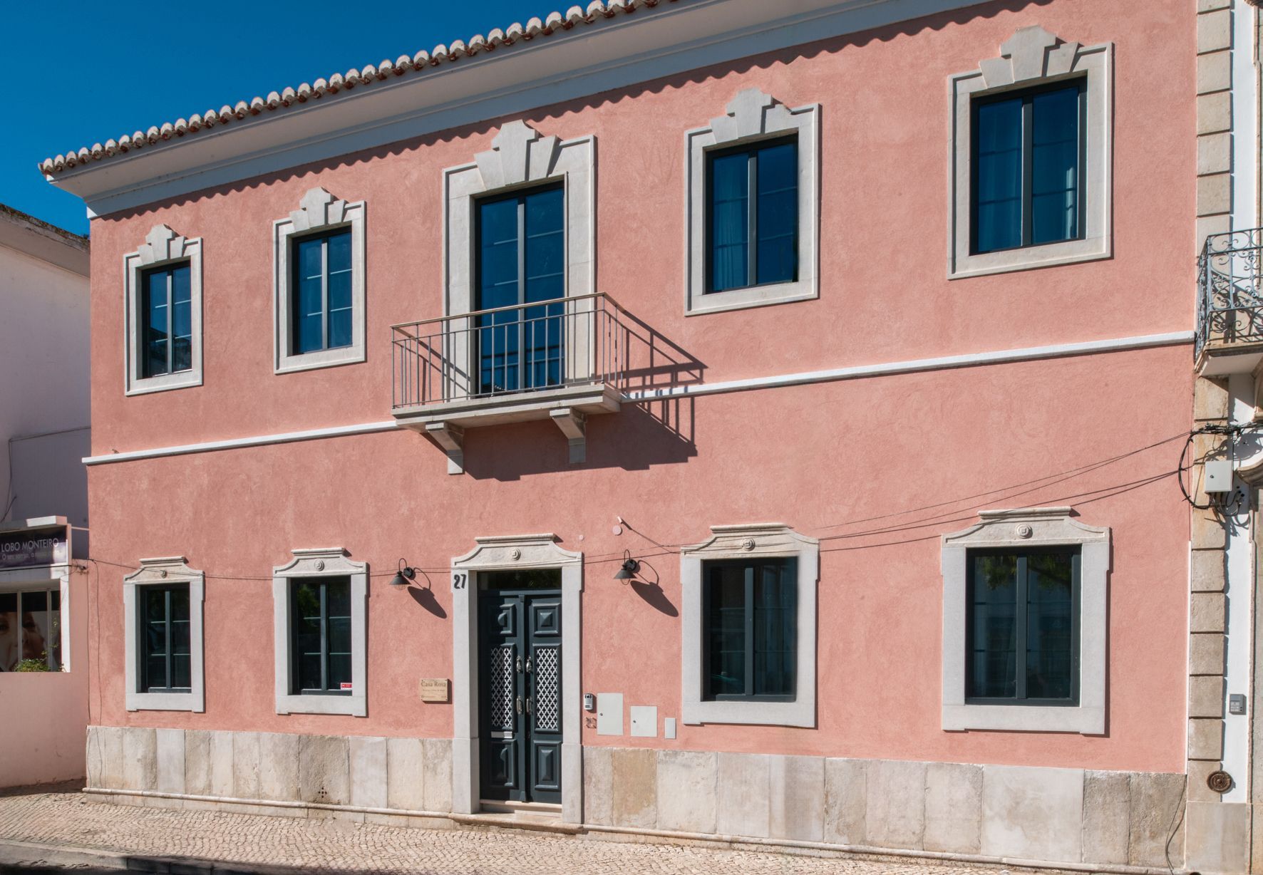 a pink building with black windows and a balcony