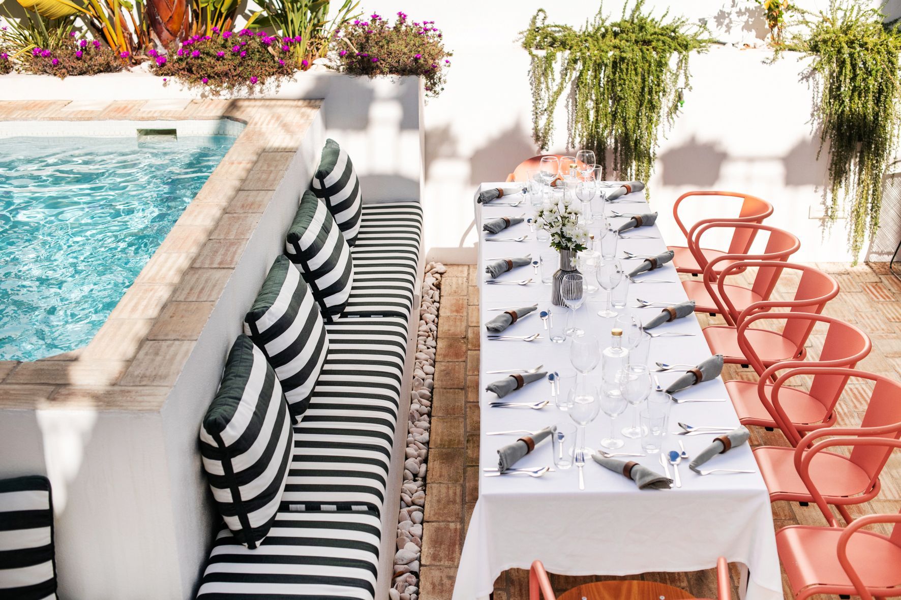 A long table is sitting next to a swimming pool.