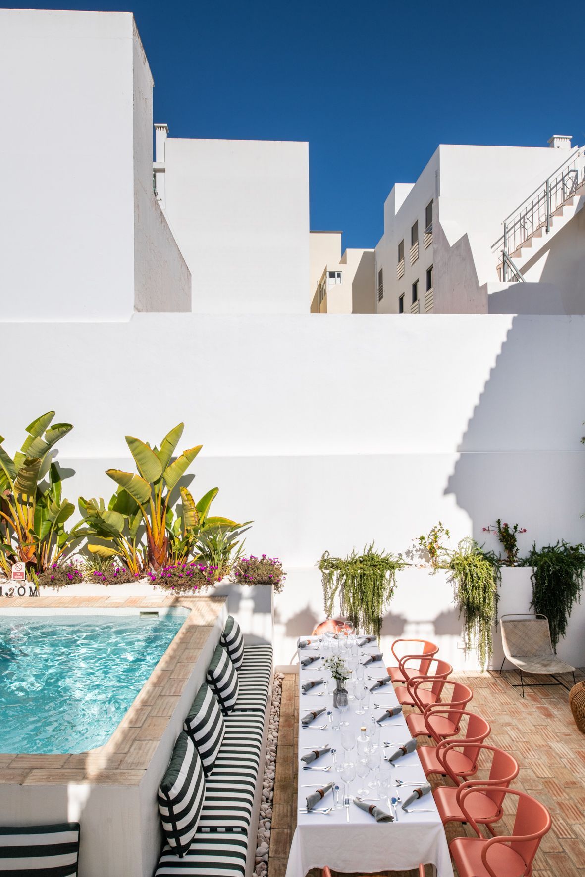 A table and chairs are set in front of a swimming pool.
