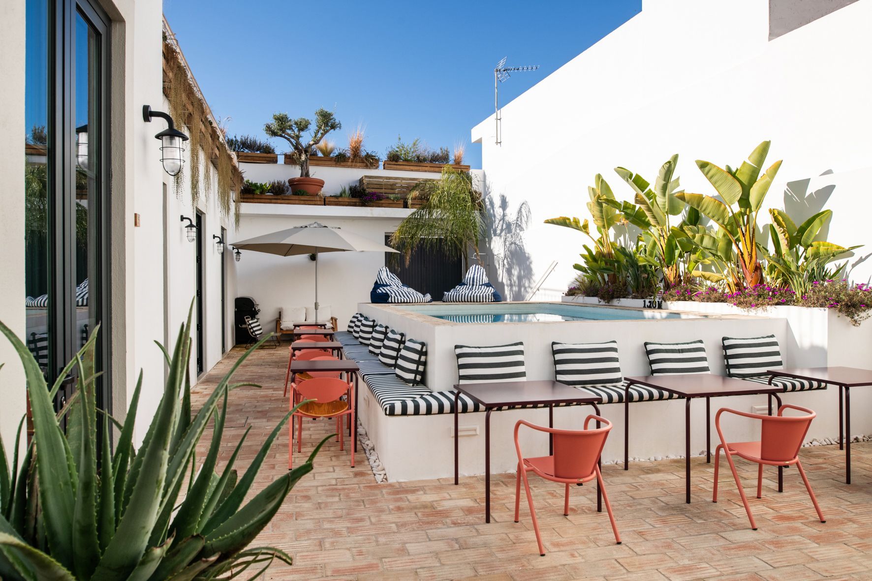 a patio with tables and chairs in front of a white building .