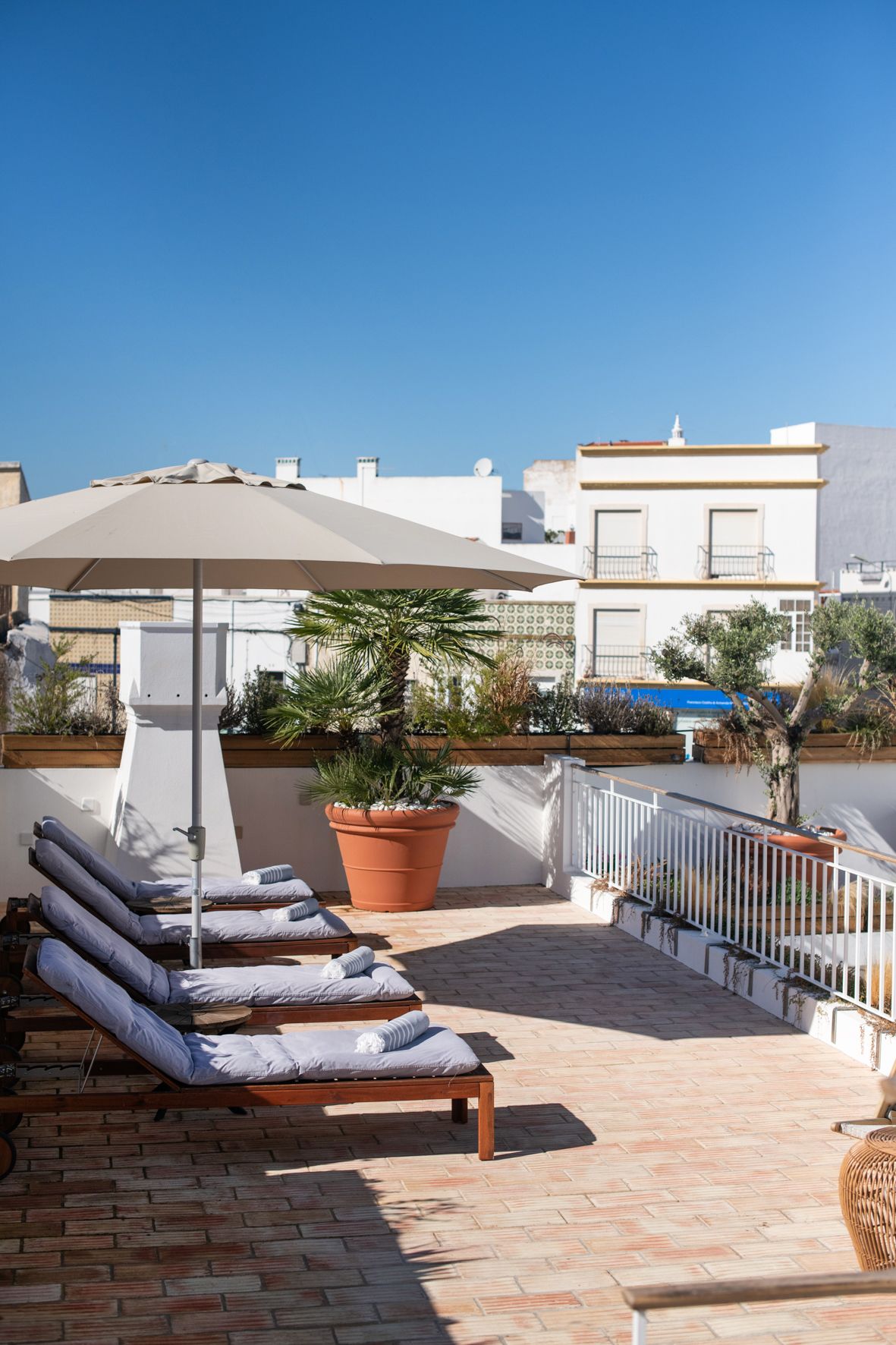 a row of lounge chairs under an umbrella on a patio .