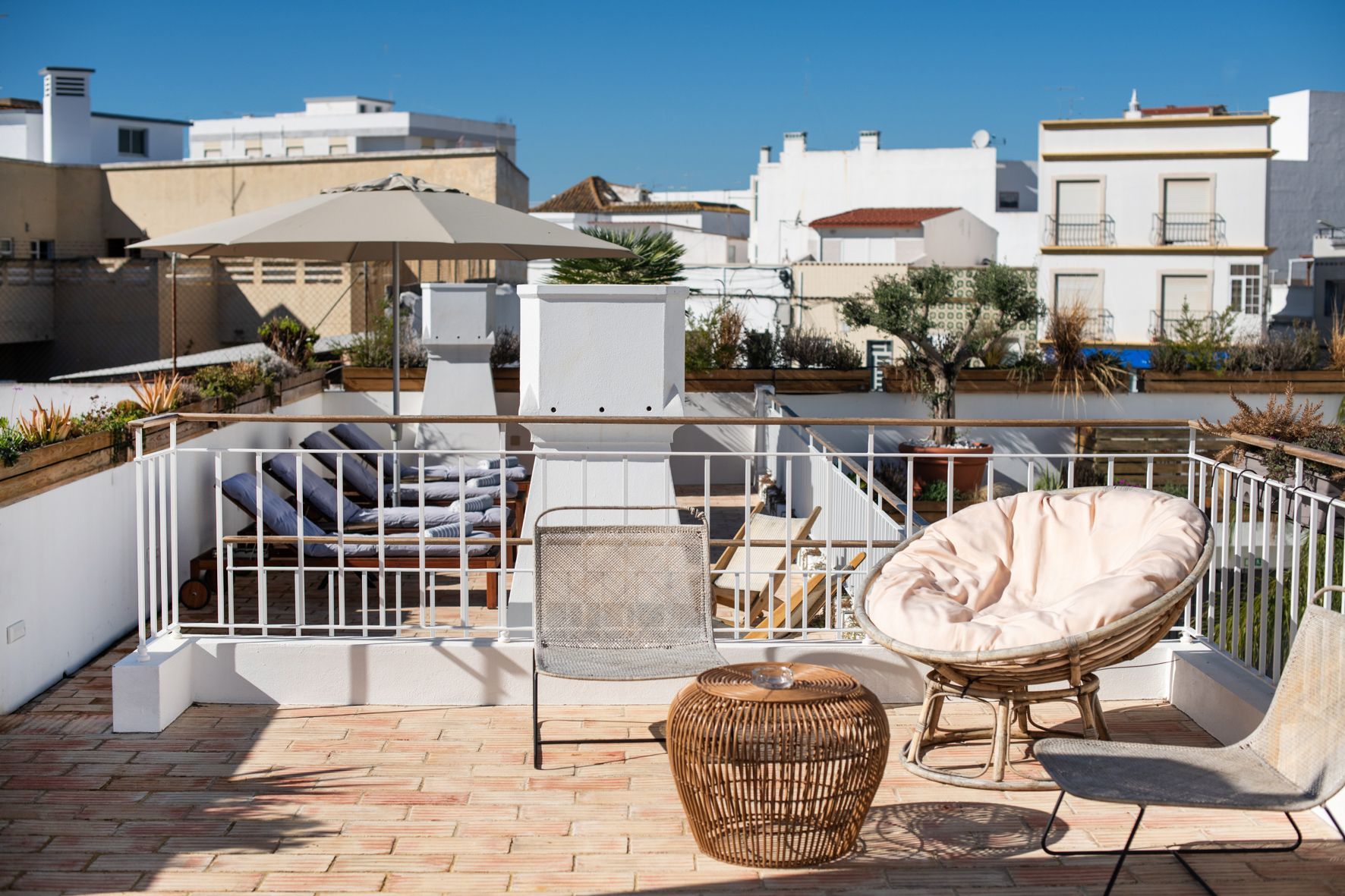 a balcony with chairs , a table and an umbrella .