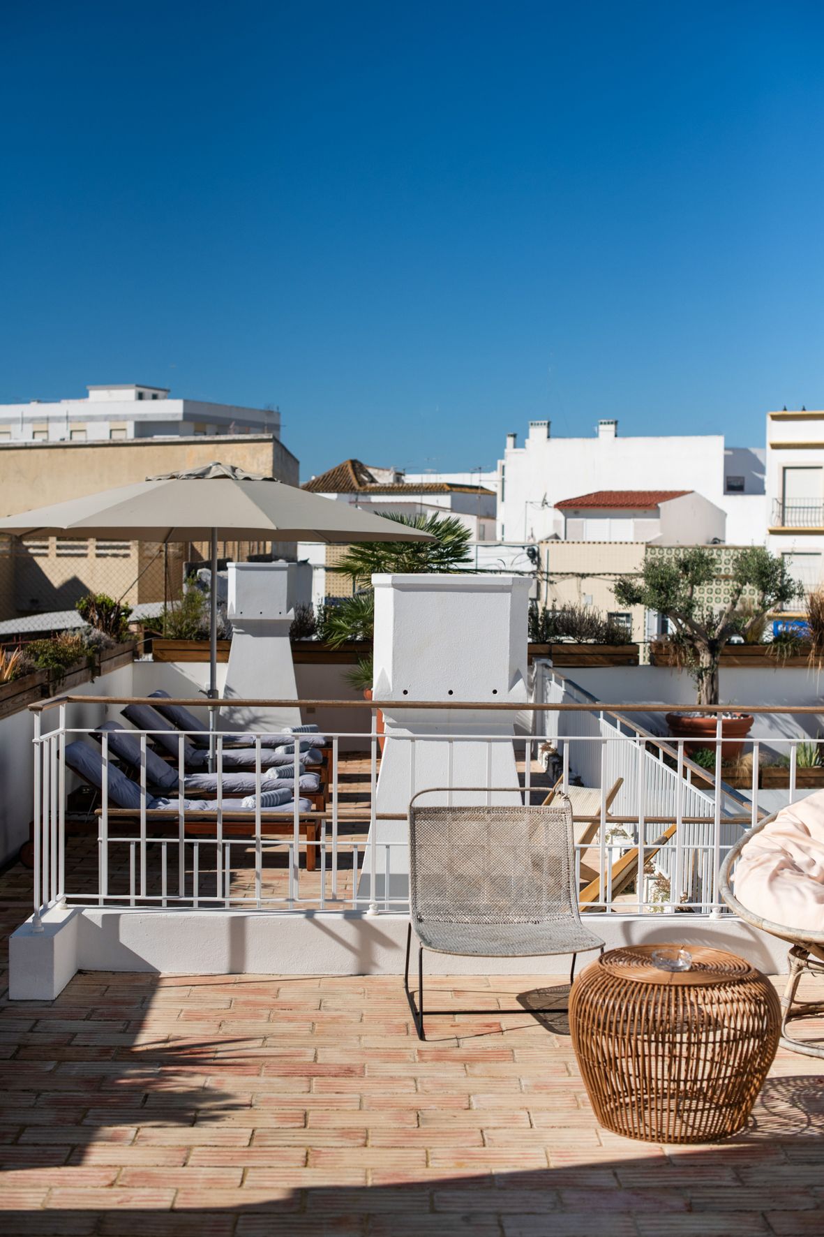 a balcony with chairs , umbrellas and a table with a view of a city .