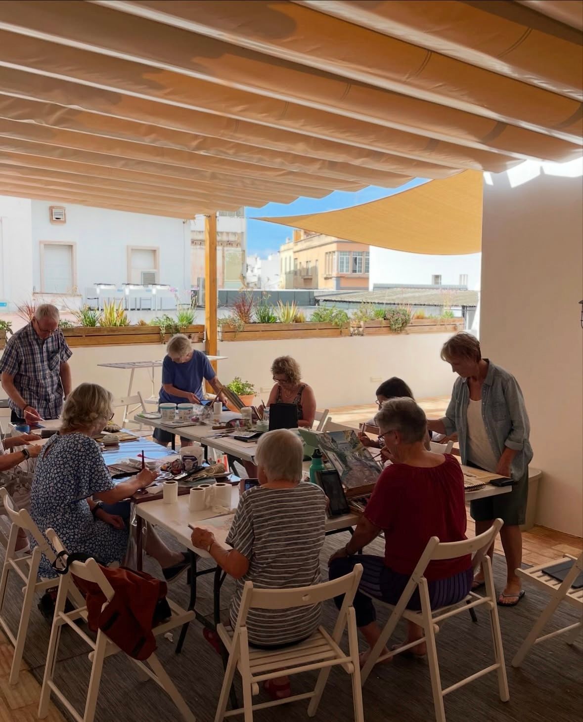 A group of people are sitting at tables under a canopy.