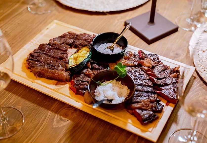 a steak and vegetables on a wooden cutting board on a wooden table .