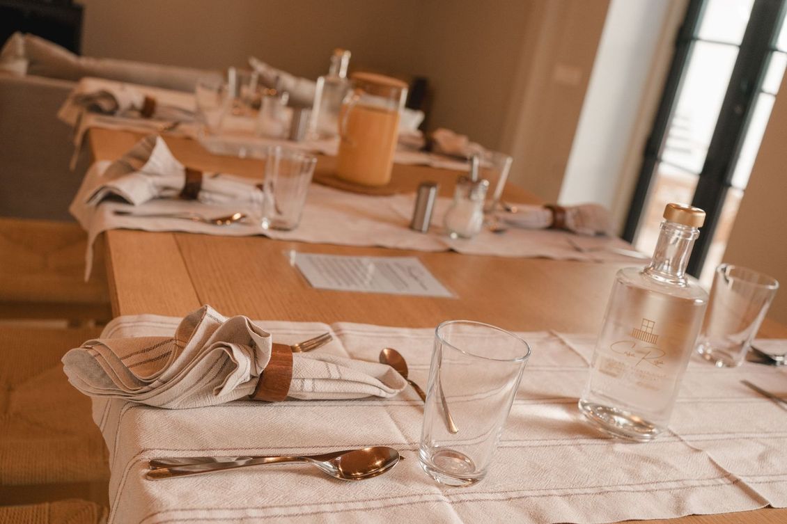 A table with a napkin , glasses , utensils and a bottle on it