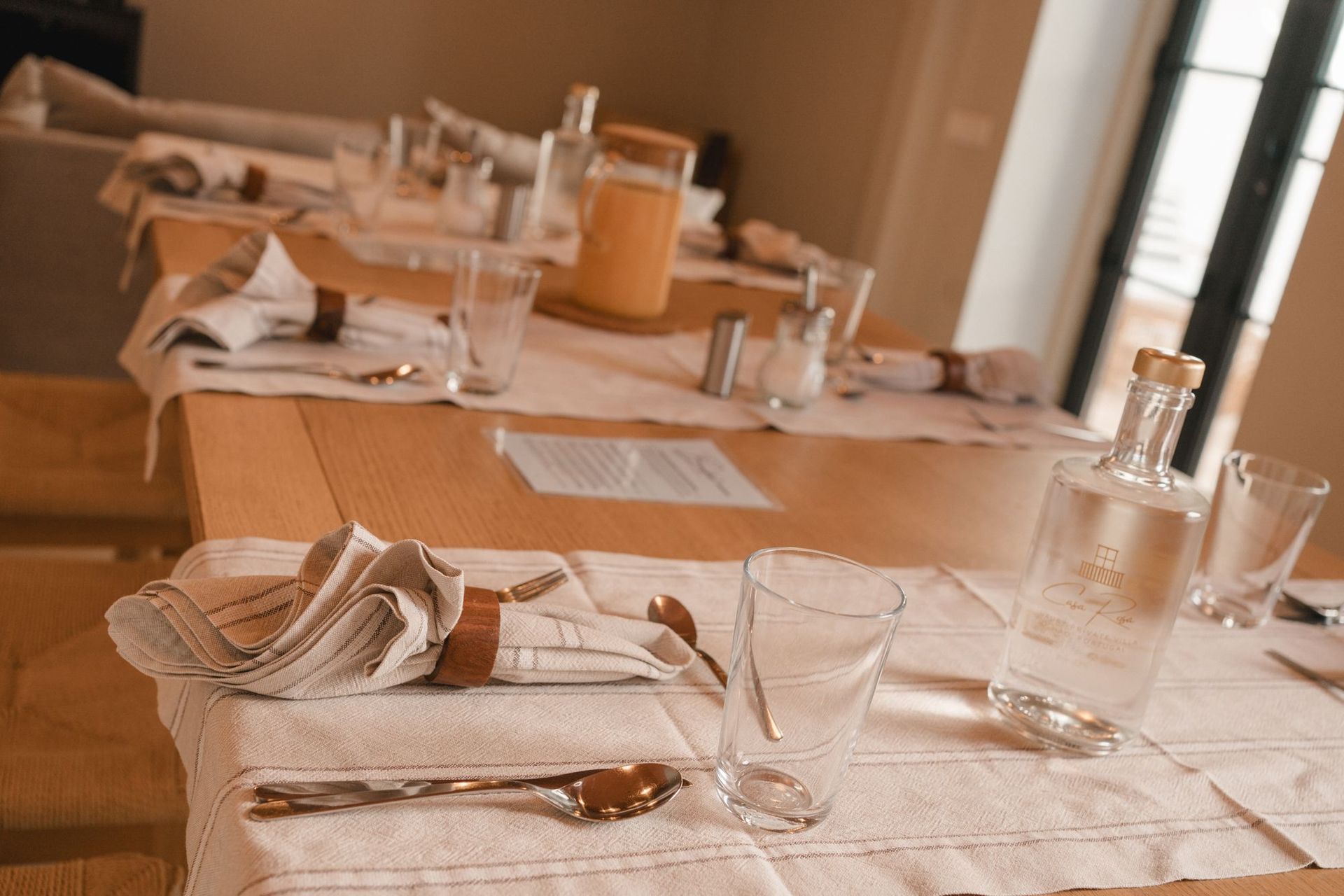 A table with a napkin , glasses , utensils and a bottle on it
