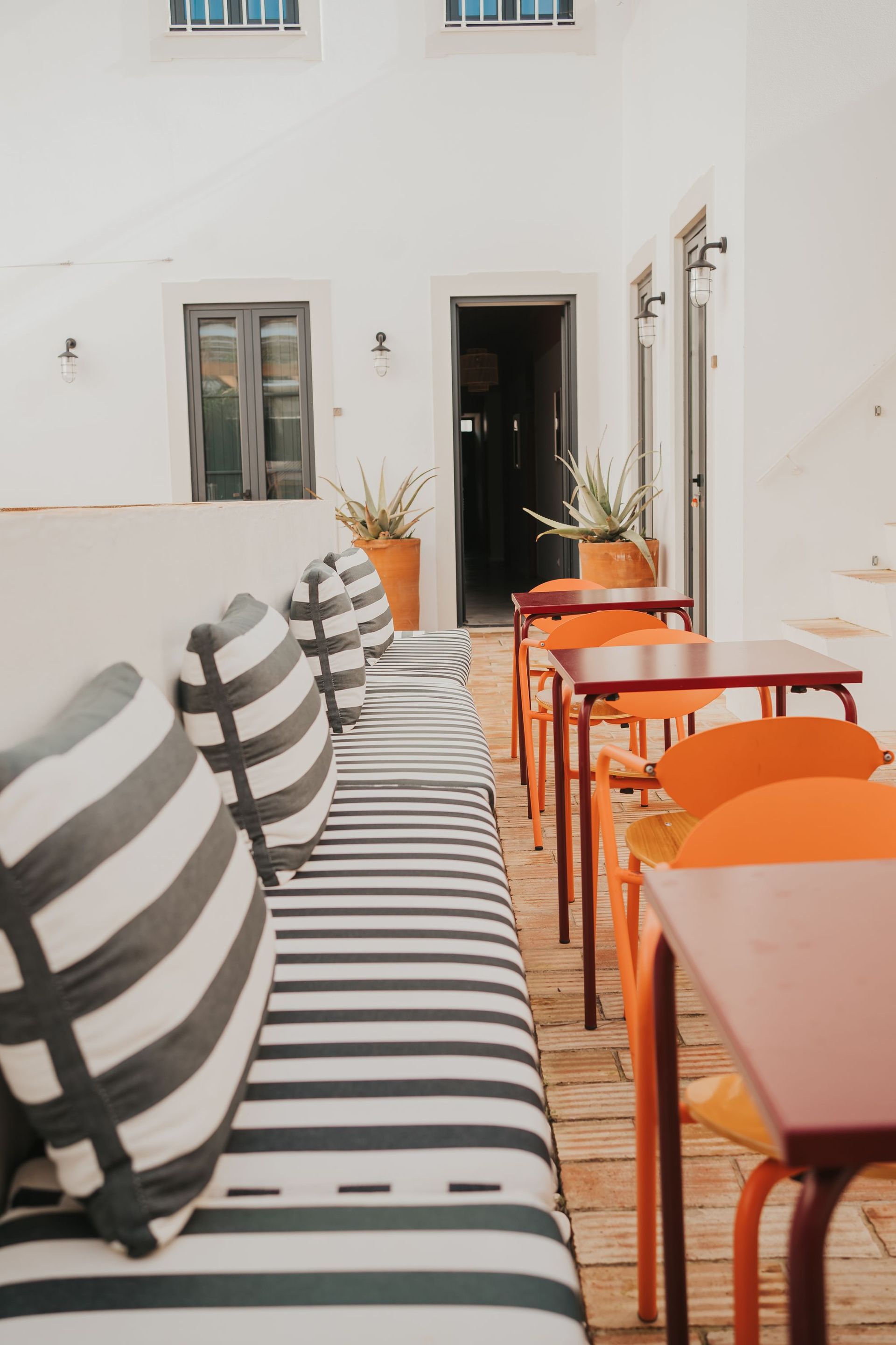 A row of tables and chairs in a room with a striped couch.