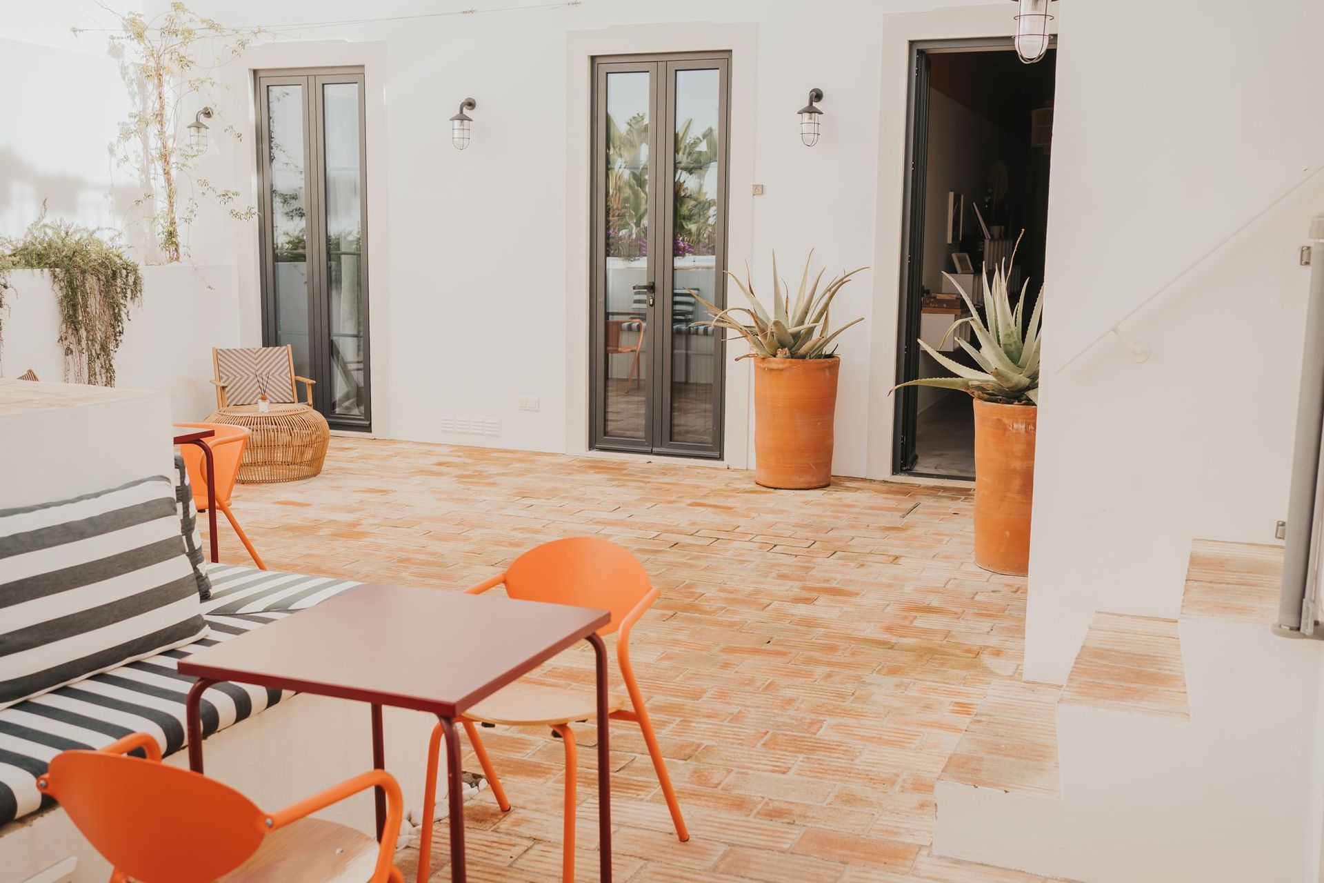 A patio with a table and chairs and a striped couch.