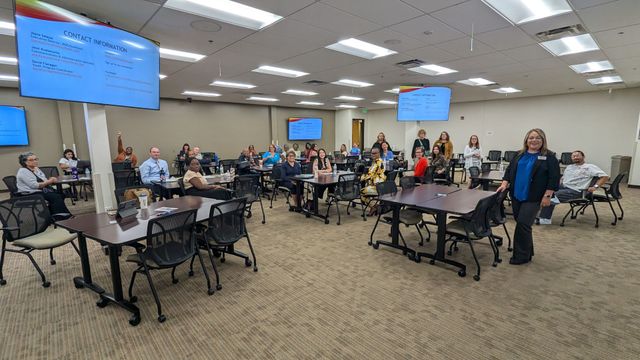 A large room filled with people sitting at tables and chairs.