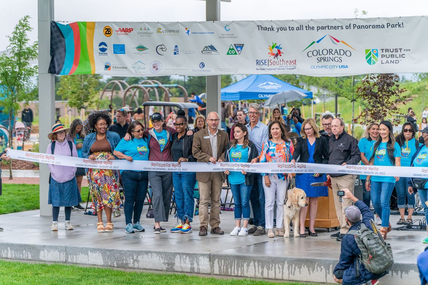 A group of people are standing in front of a ribbon cutting ceremony for Panorama Park.