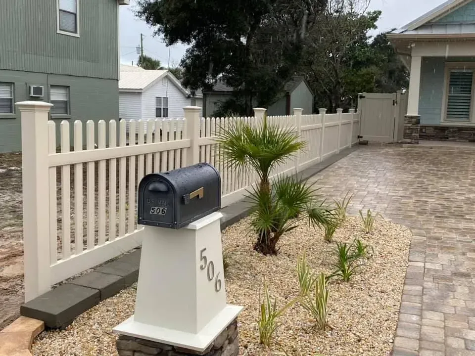 Mailbox and house number 50 beside a white picket fence and landscaped front yard.