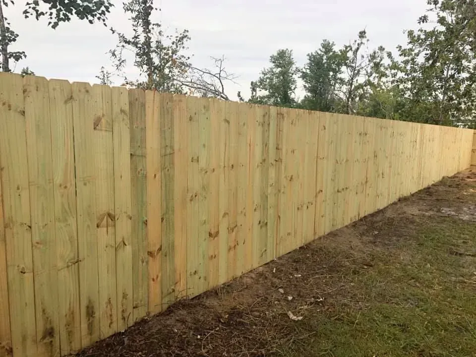 New wooden privacy fence along a grassy yard under overcast sky