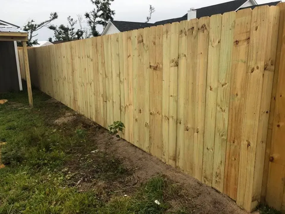 New wooden privacy fence along a grassy yard under an overcast sky
