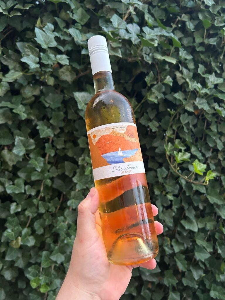 Bottle of Grande Absente absinthe liqueur, green and white label, set on dried herbs.