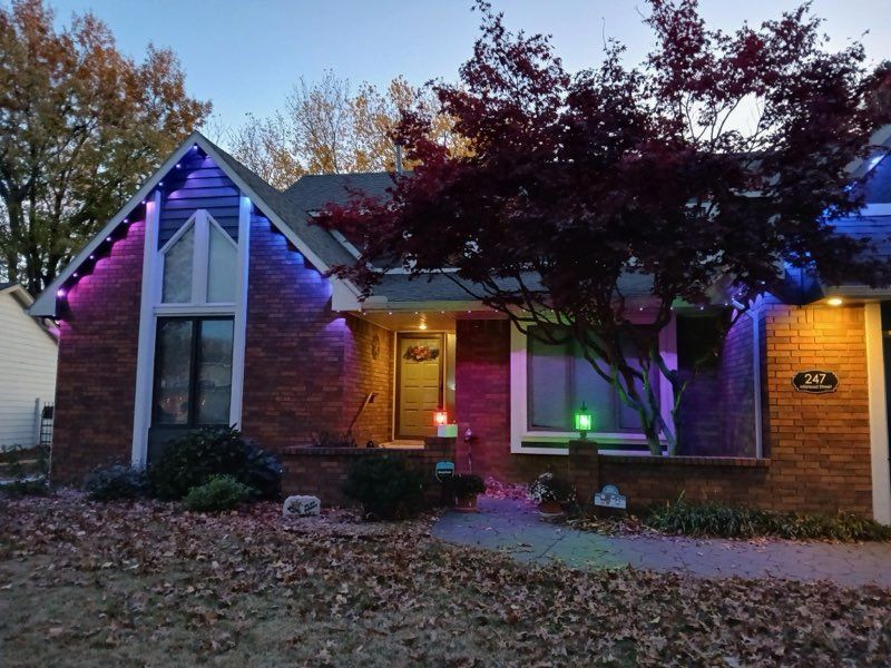 A brick house with purple and green lights on it
