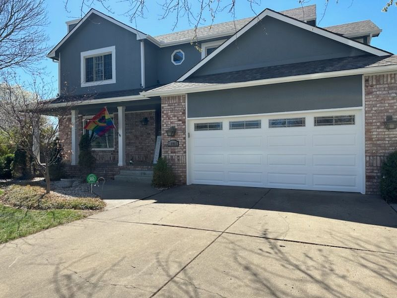 A large house with a white garage door and a rainbow flag on the front.