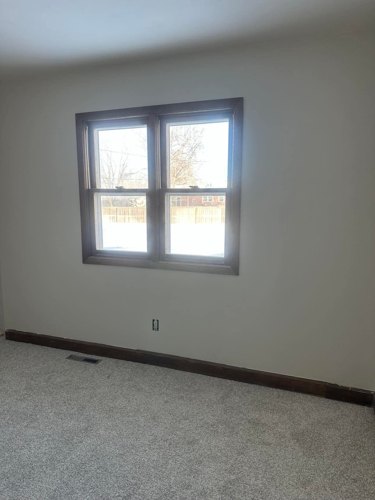 An empty room with two windows and a carpeted floor.