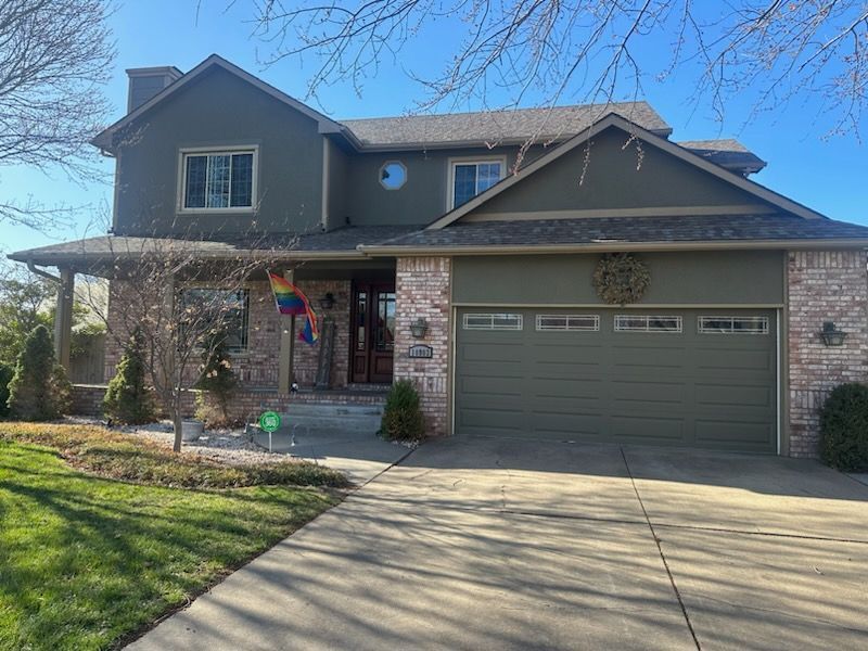 A large house with a green garage door and a brick facade.