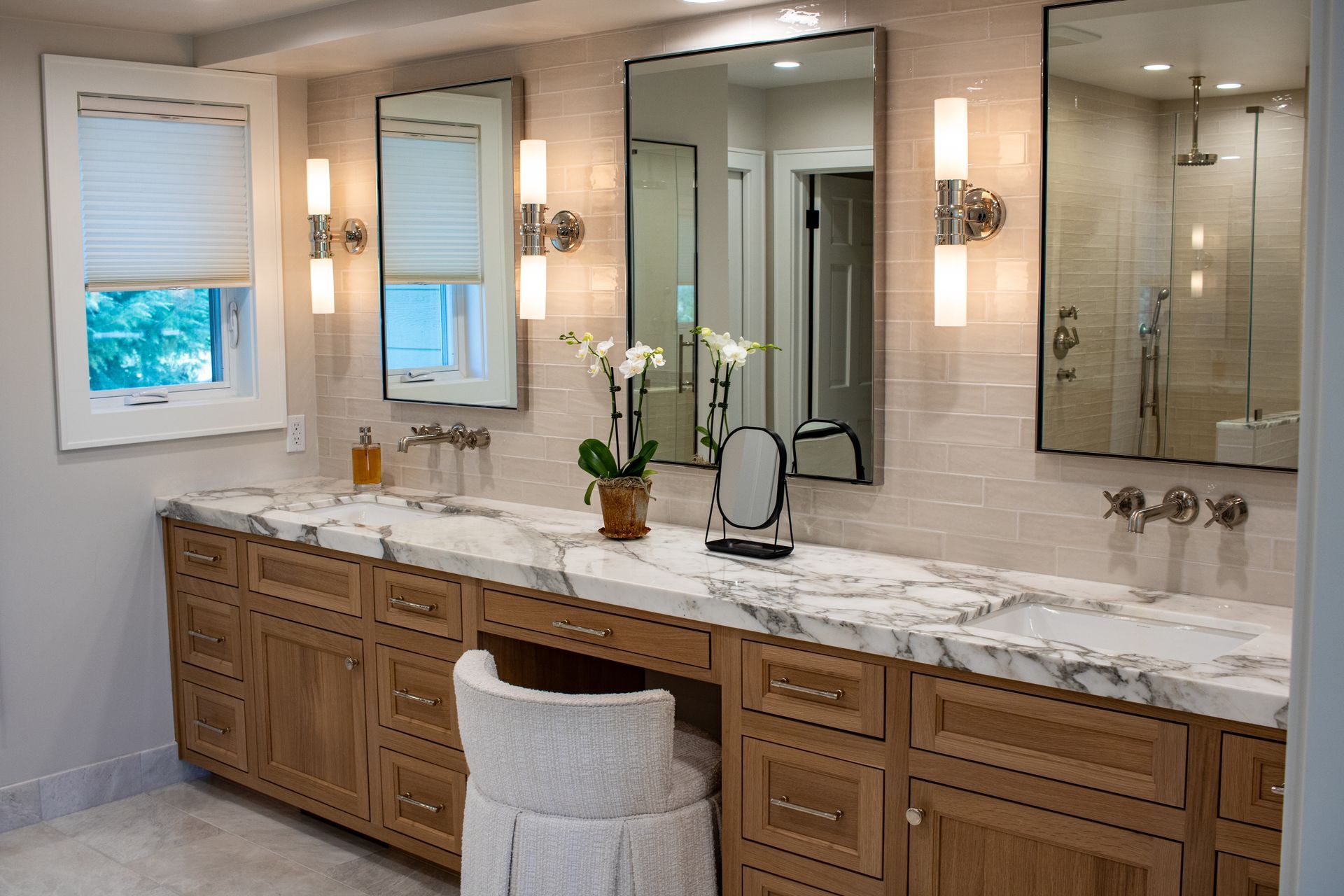 Bathroom with double vanity, marble countertop, wooden cabinets, two mirrors, and a makeup area.