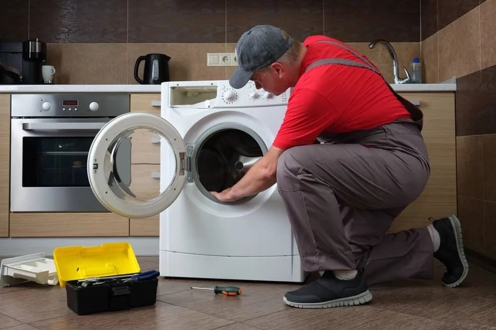 A Technician Repairs a White Washing Machine — Central Coast Washing Machines & Refrigerator Repairs in San Remo, NSW