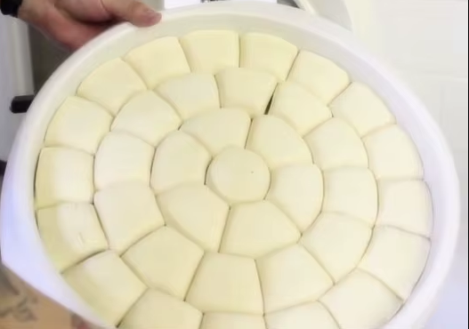 Maquina prensadora de masa en acero inoxidable con tapa blanca, sobre ruedas.