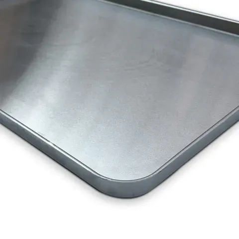 Una bandeja para hornear rectangular, plateada, con un borde ligeramente elevado.