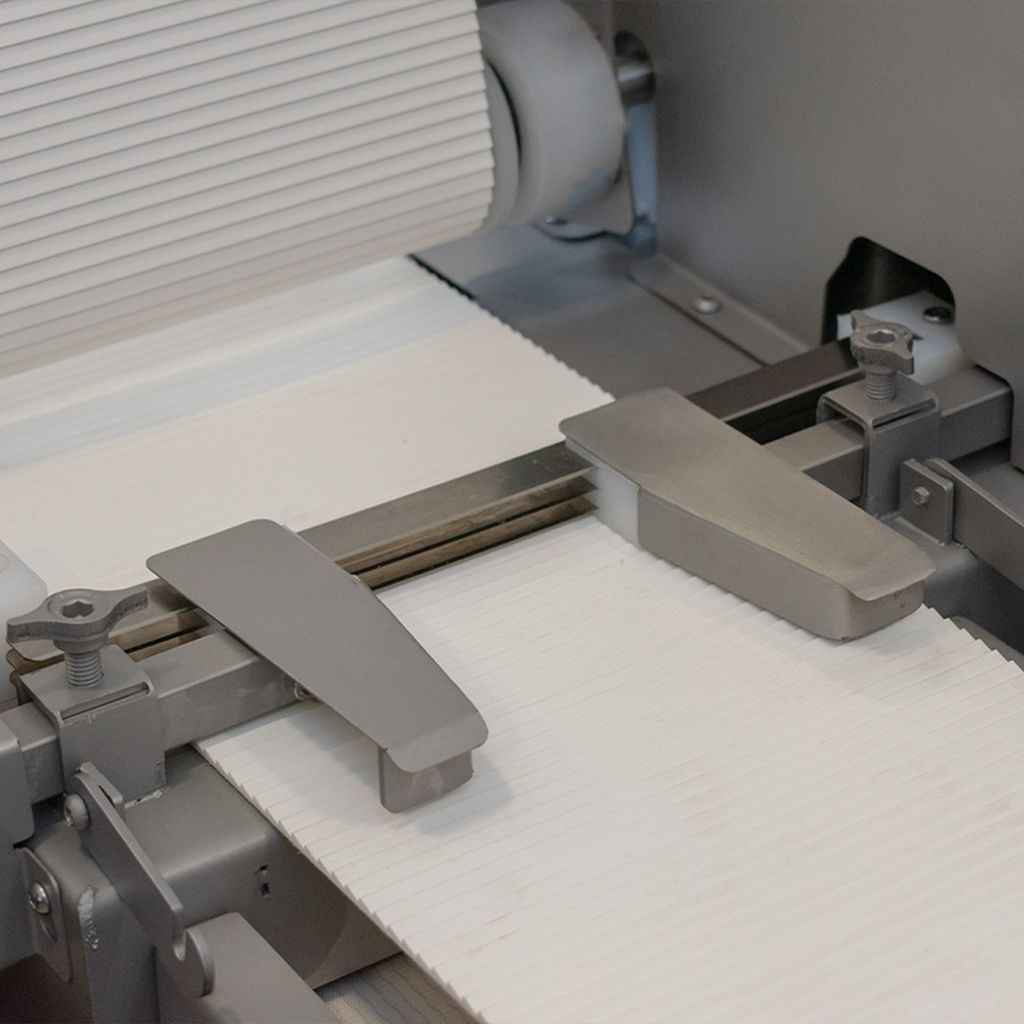 Máquina procesadora de alimentos de acero inoxidable con cintas transportadoras y panel de control.
