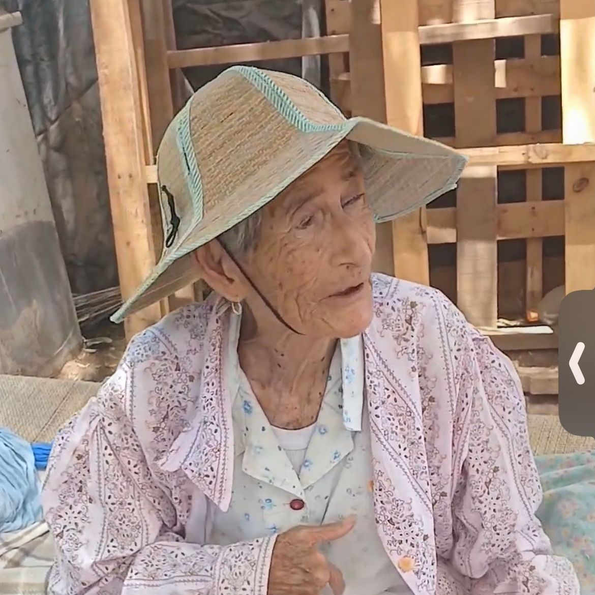 An elderly woman wearing a straw hat and a pink jacket