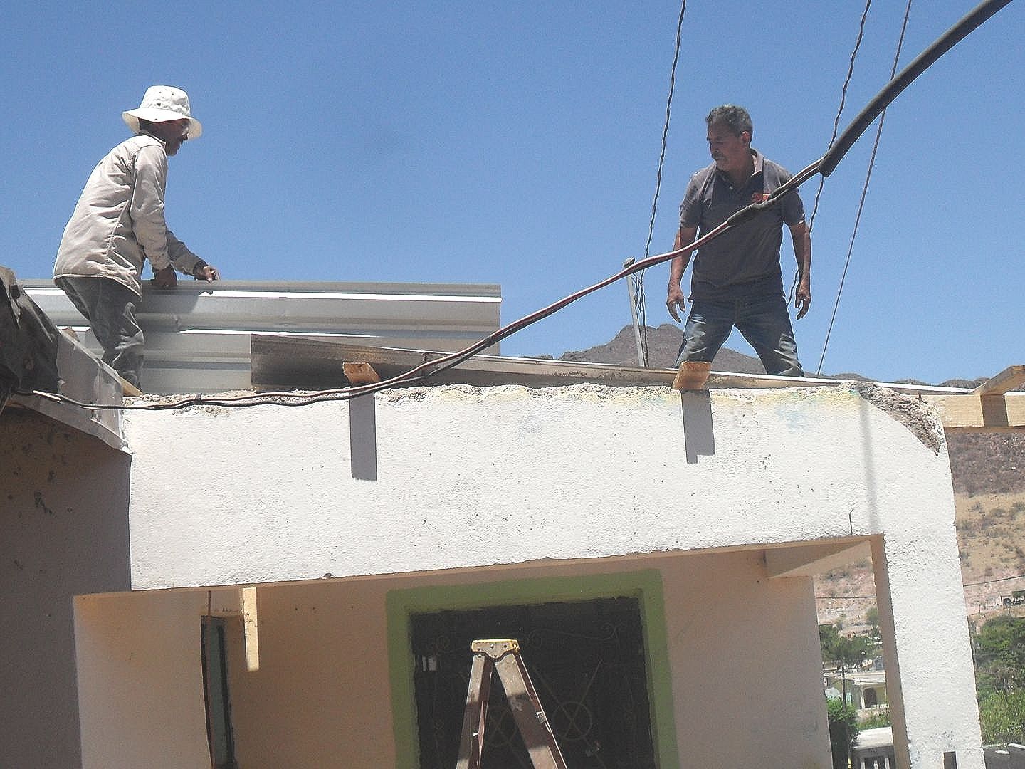 Two men are working on the roof of a building