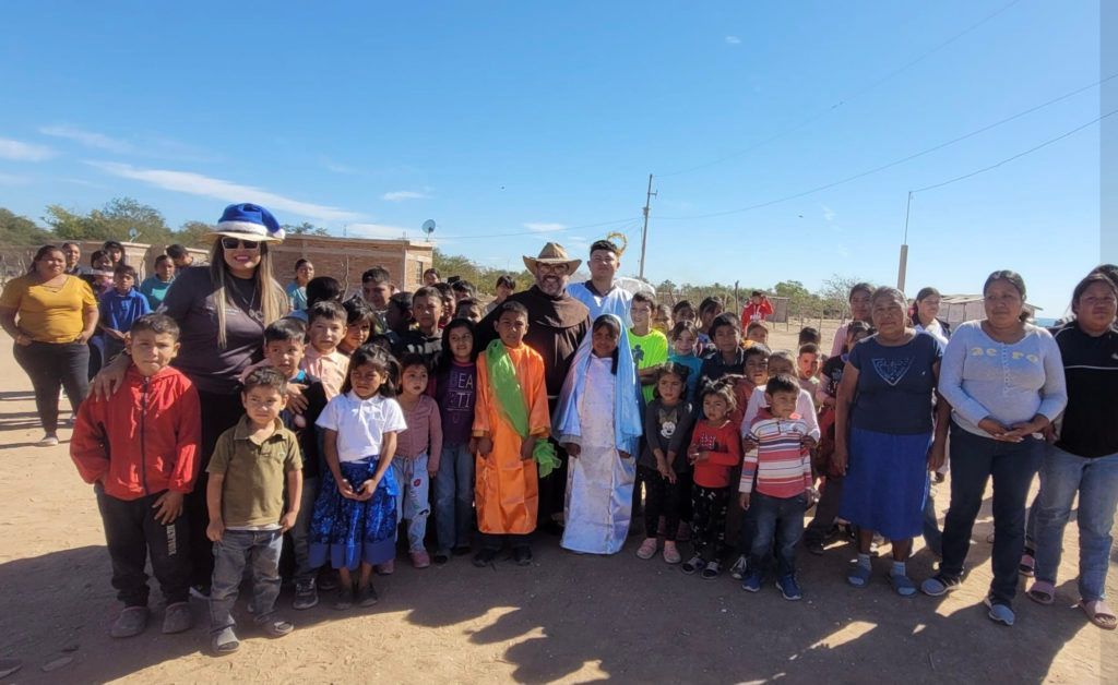 A group of people are posing for a picture in a dirt field.