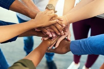 A group of people are putting their hands together.