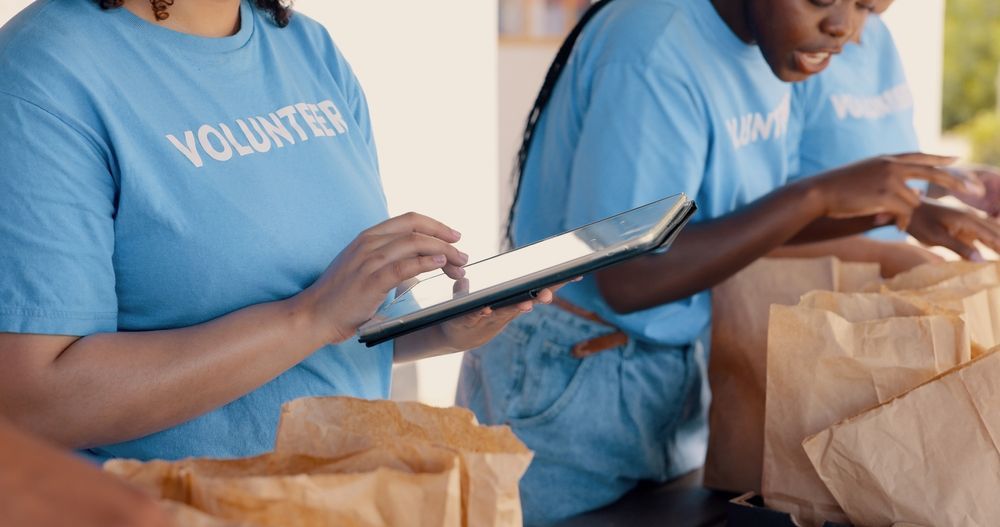 Two volunteers are looking at a tablet while standing next to each other.