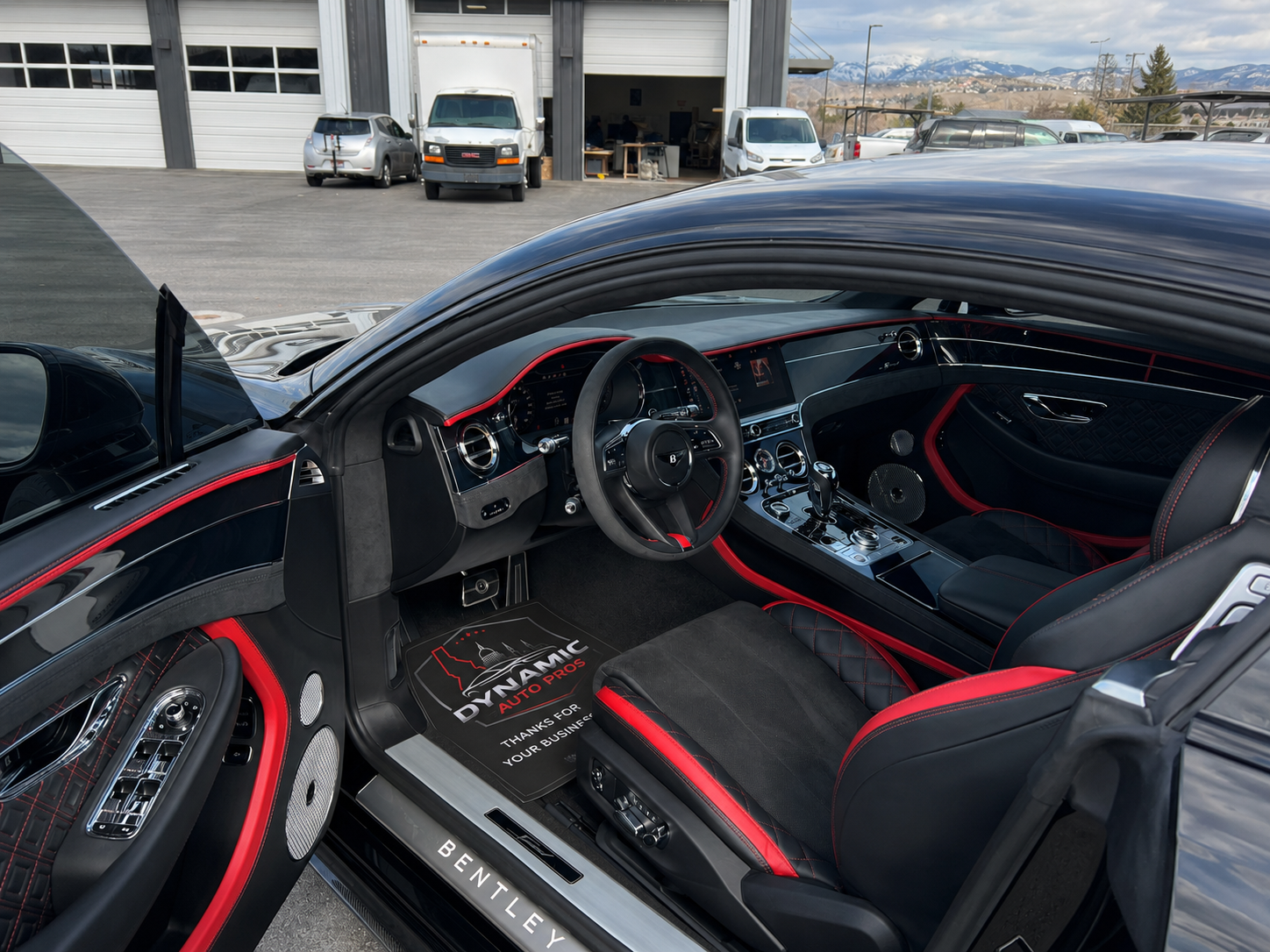 The interior of a Bentley with black and red seats is shown with the door open.