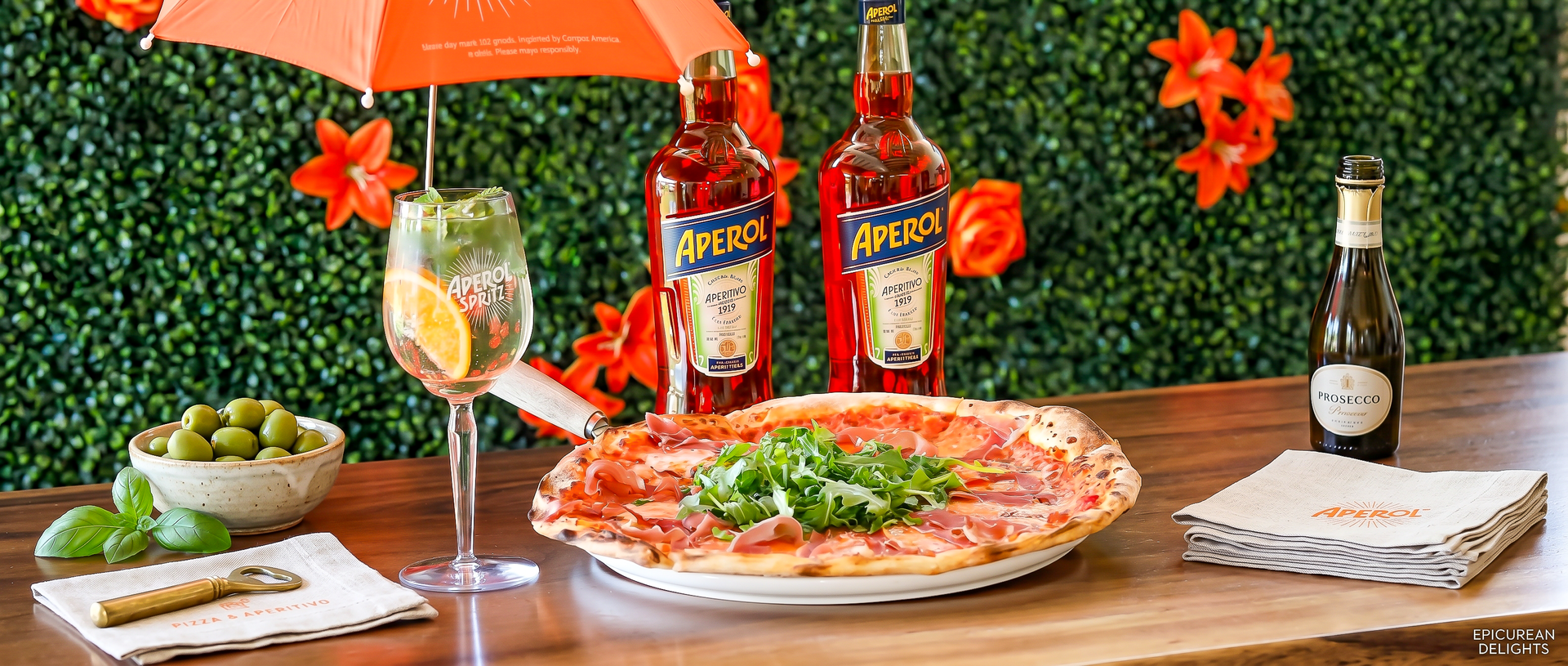 Pizza and liquor bottles on a table with orange decor and a bottle in the background