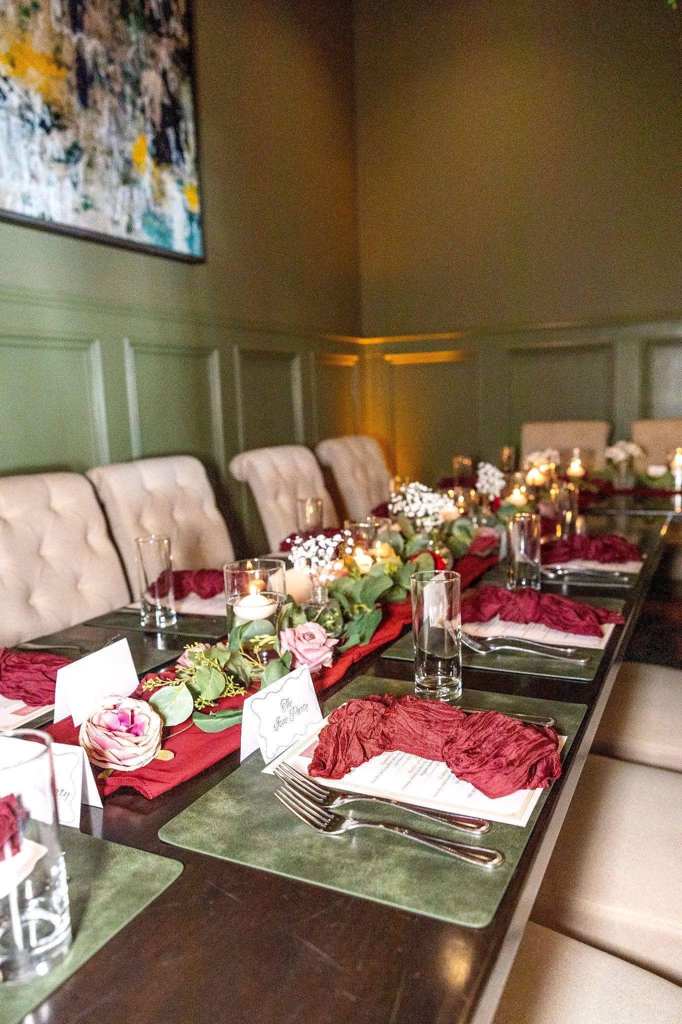 Elegant dining table set with flowers, folded napkins, and candles in a softly lit restaurant room