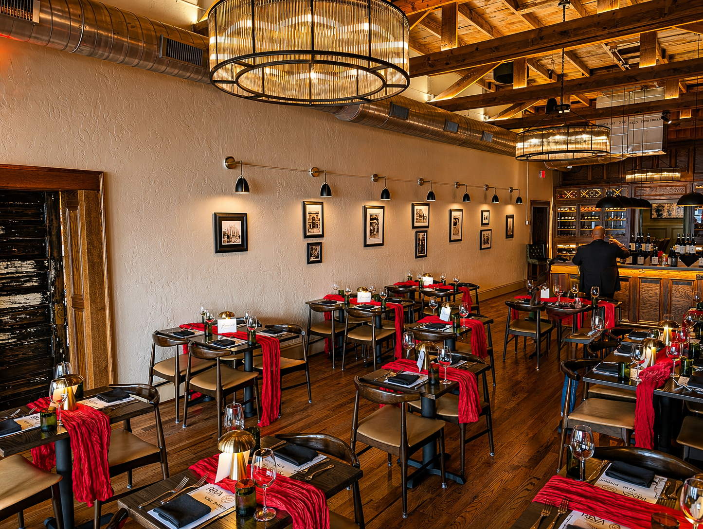 Elegant restaurant dining room with red-accented tables, warm lighting, and chandeliers
