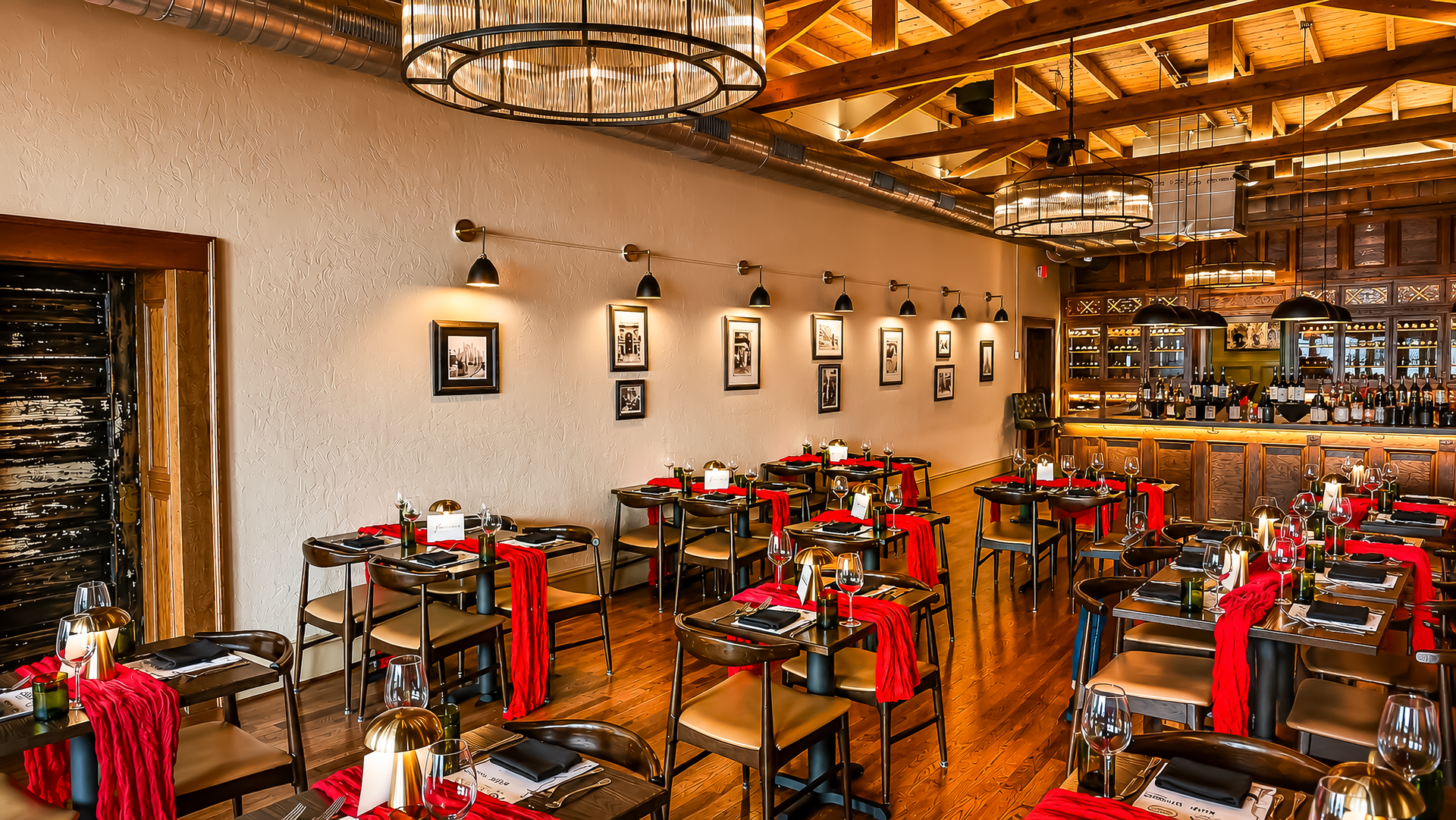Modern restaurant dining room with red chairs, warm lighting, and framed wall art
