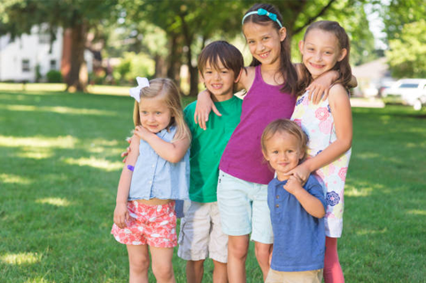 A group of children are posing for a picture in a park.