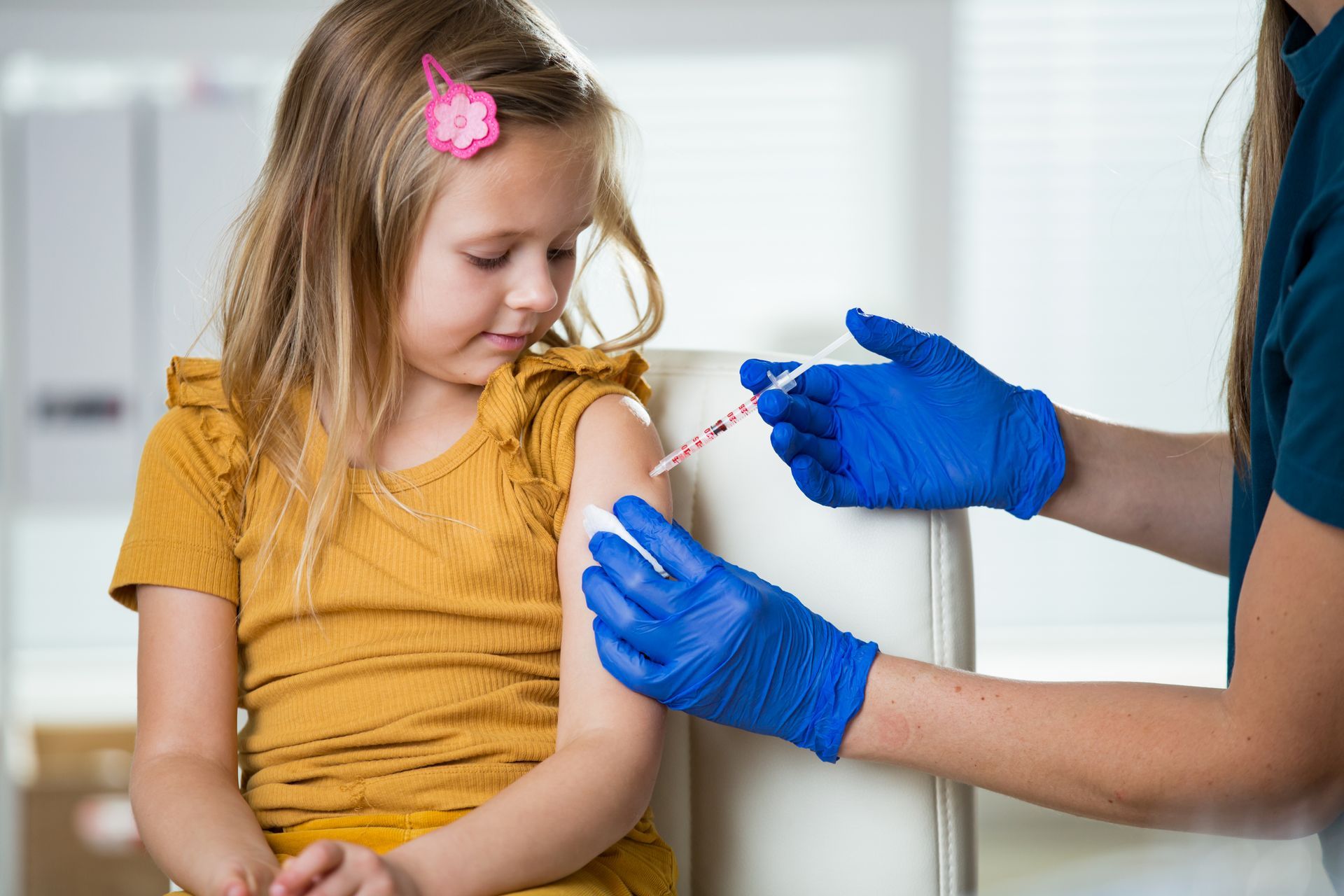 A little girl is getting an injection in her arm.