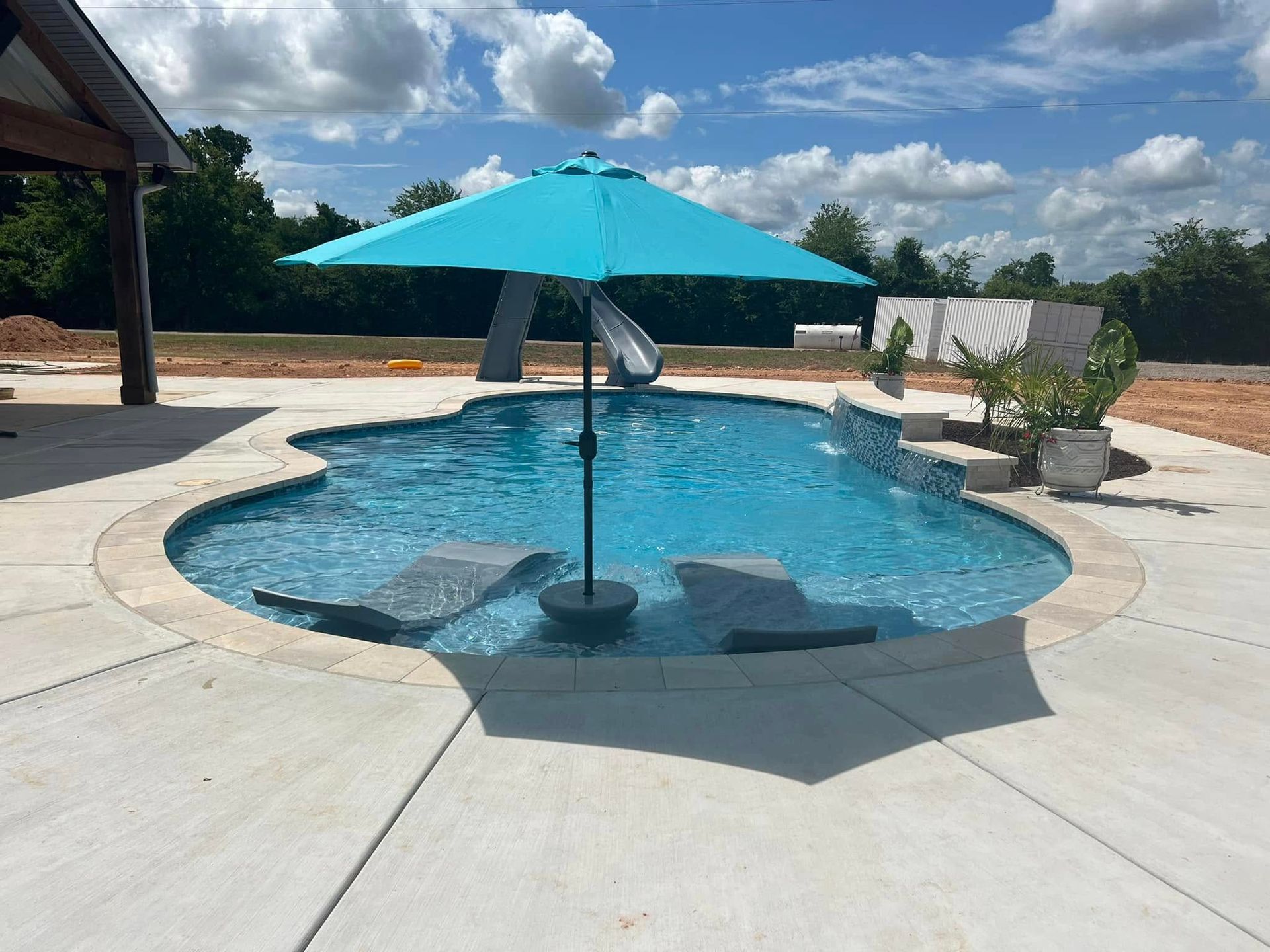A large swimming pool with a blue umbrella in the middle.