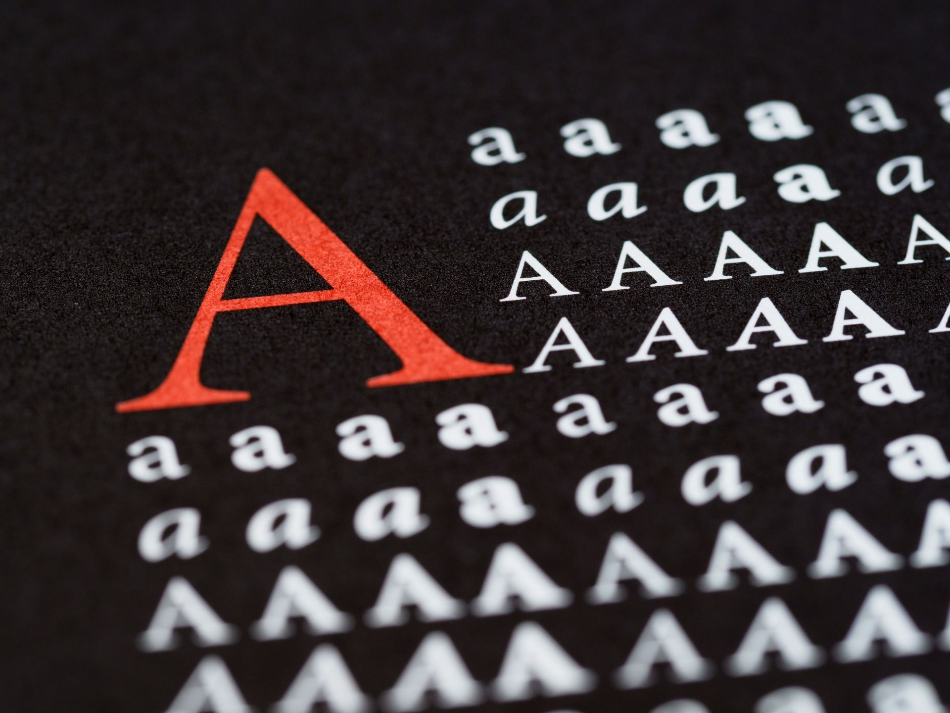 Large red capital A among rows of white lowercase a letters on a black background