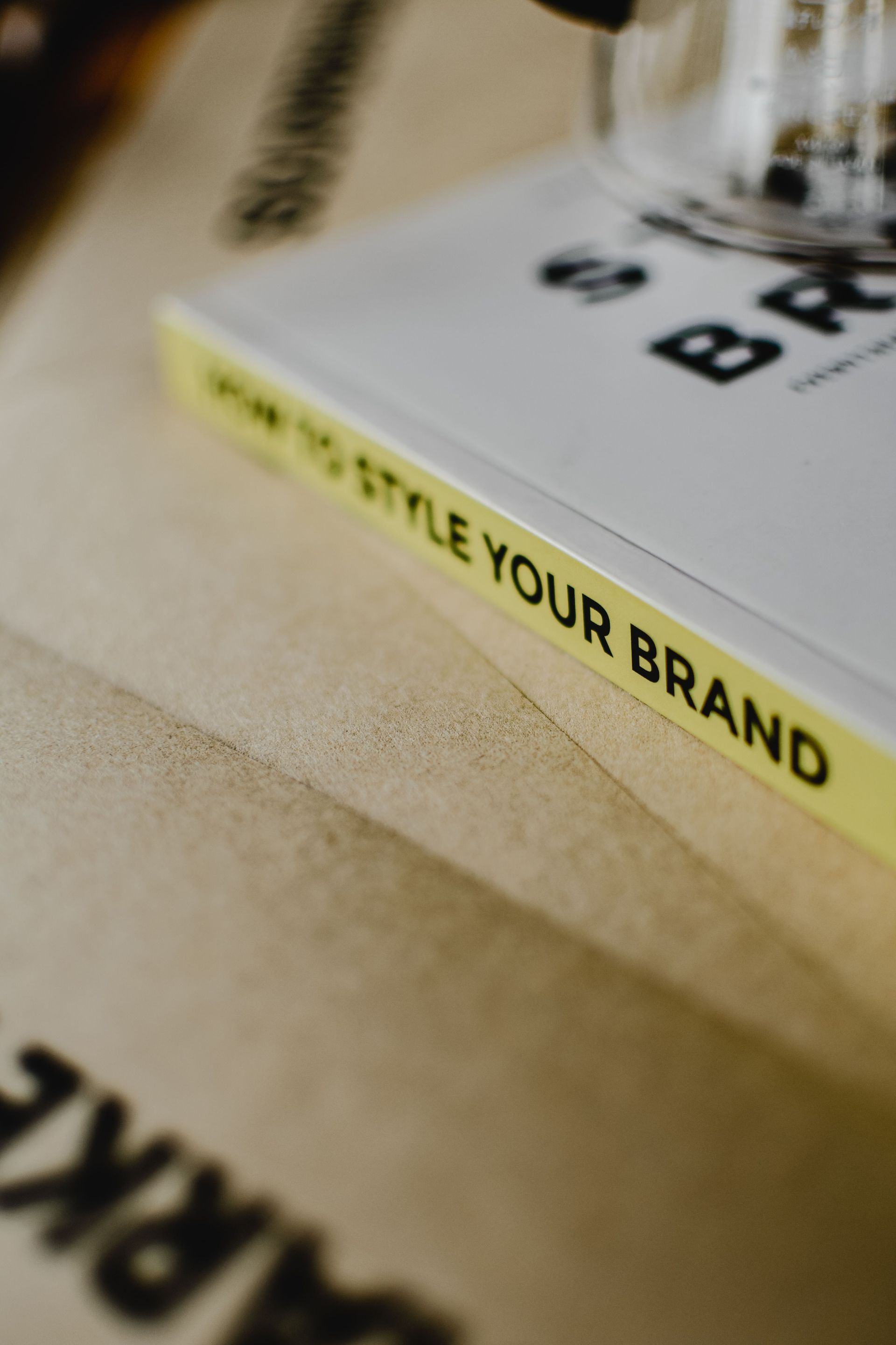 Close-up of a branded notebook on a beige surface with yellow edge and a pen holder.