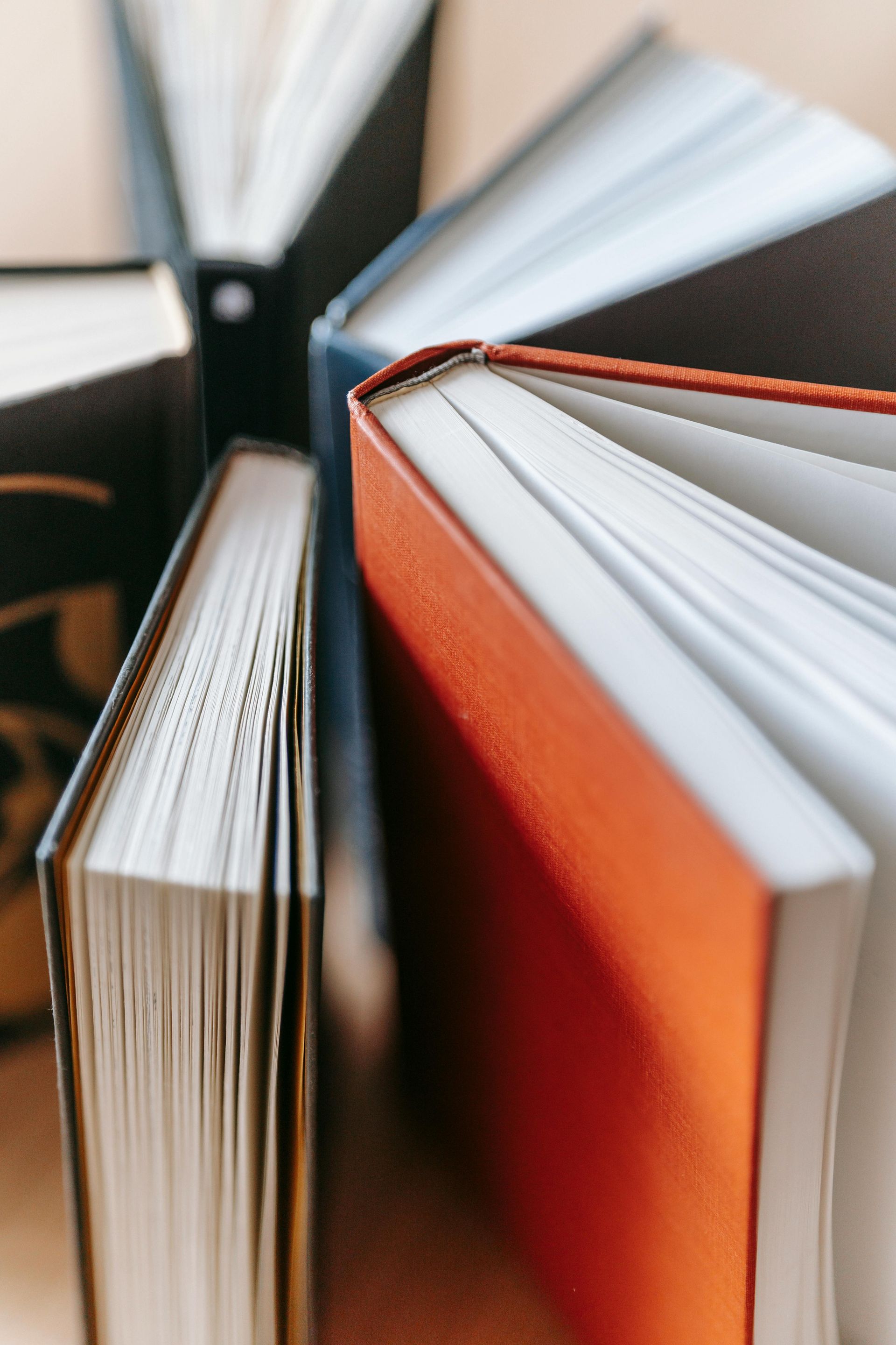 Close-up of stacked books with orange and black covers, showing white pages