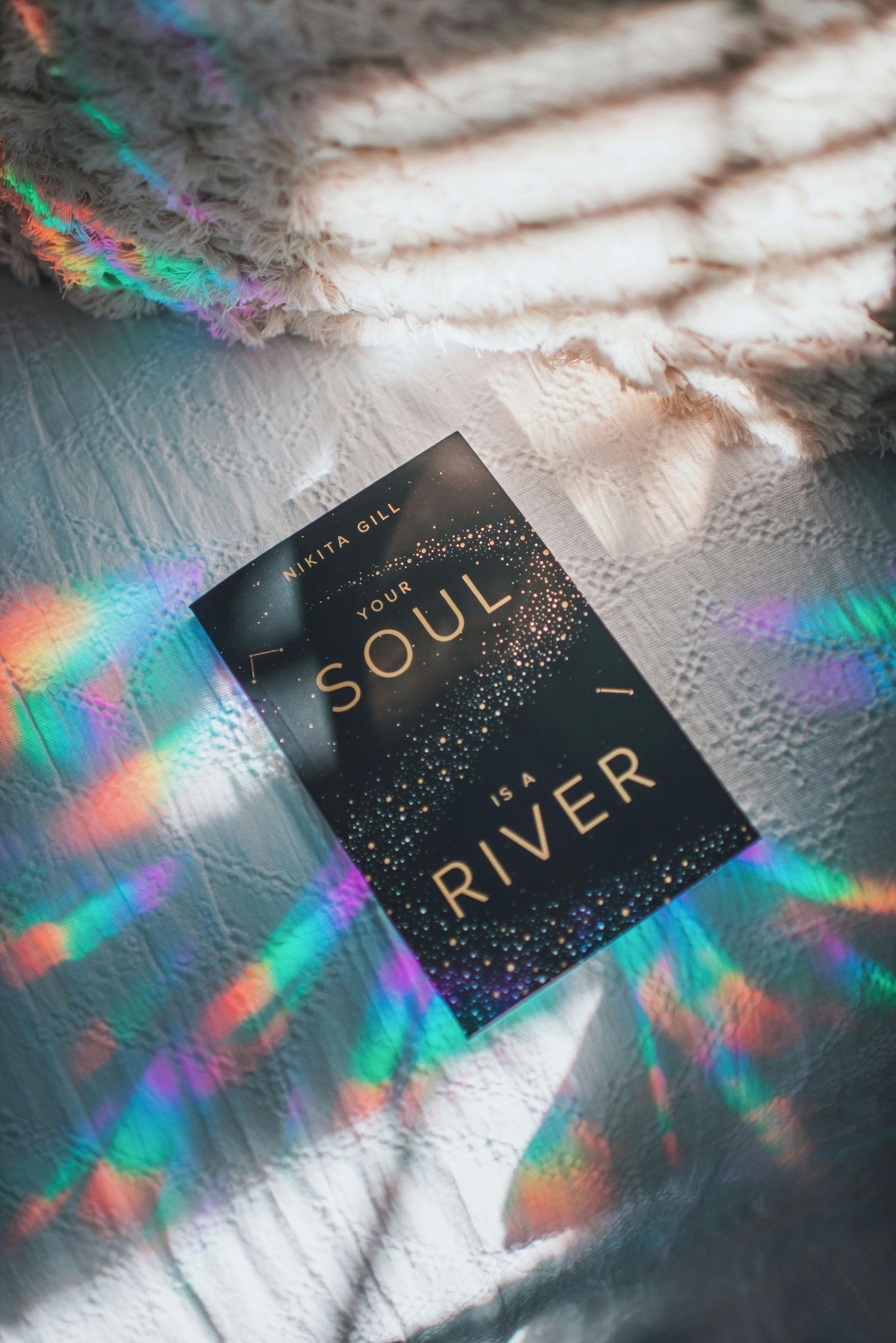 A book called soul river is sitting on a table with a rainbow reflection.