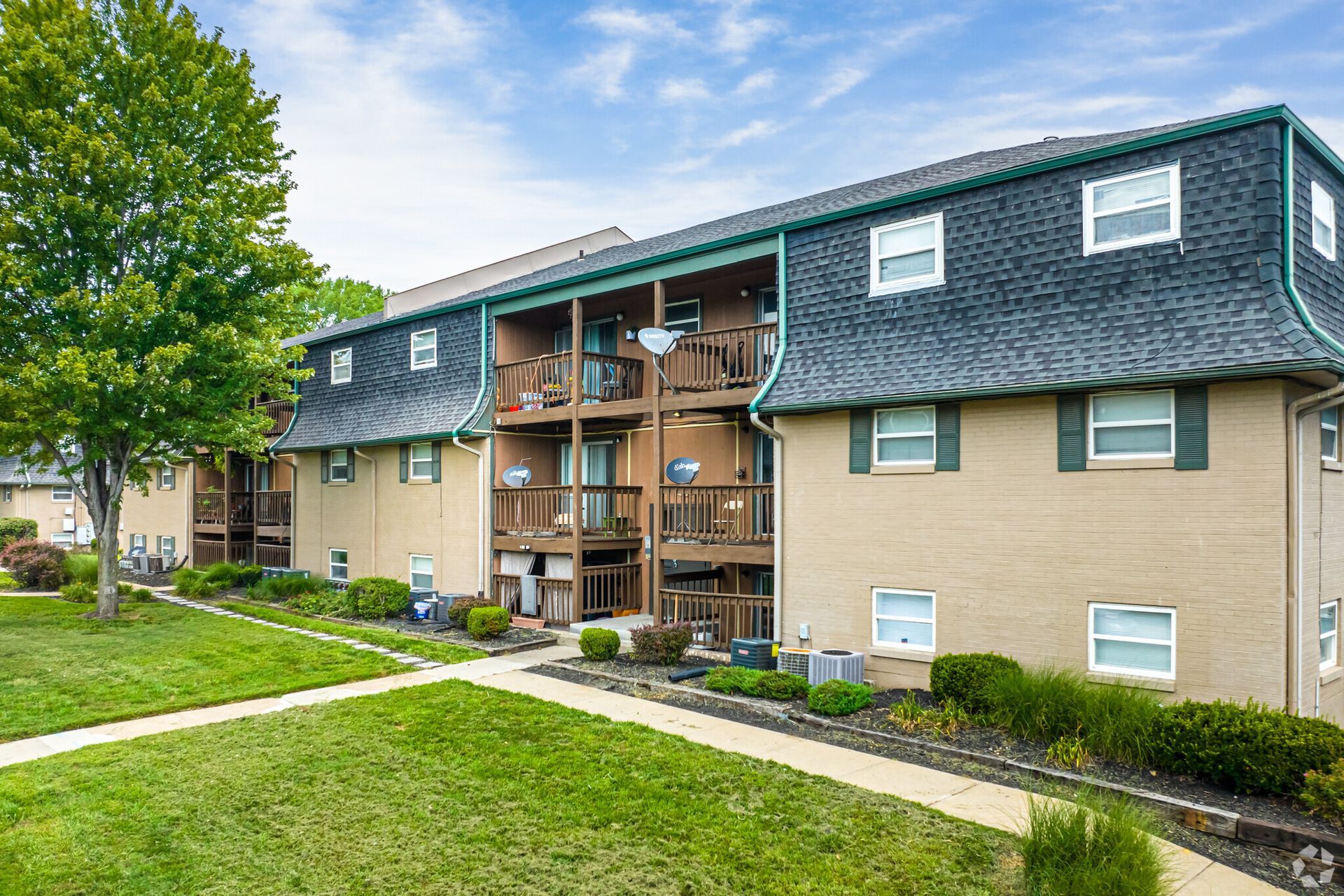 A large apartment building with a lush green lawn in front of it.