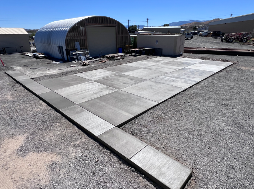 Outdoor view of a paved concrete pad beside a curved metal building under construction